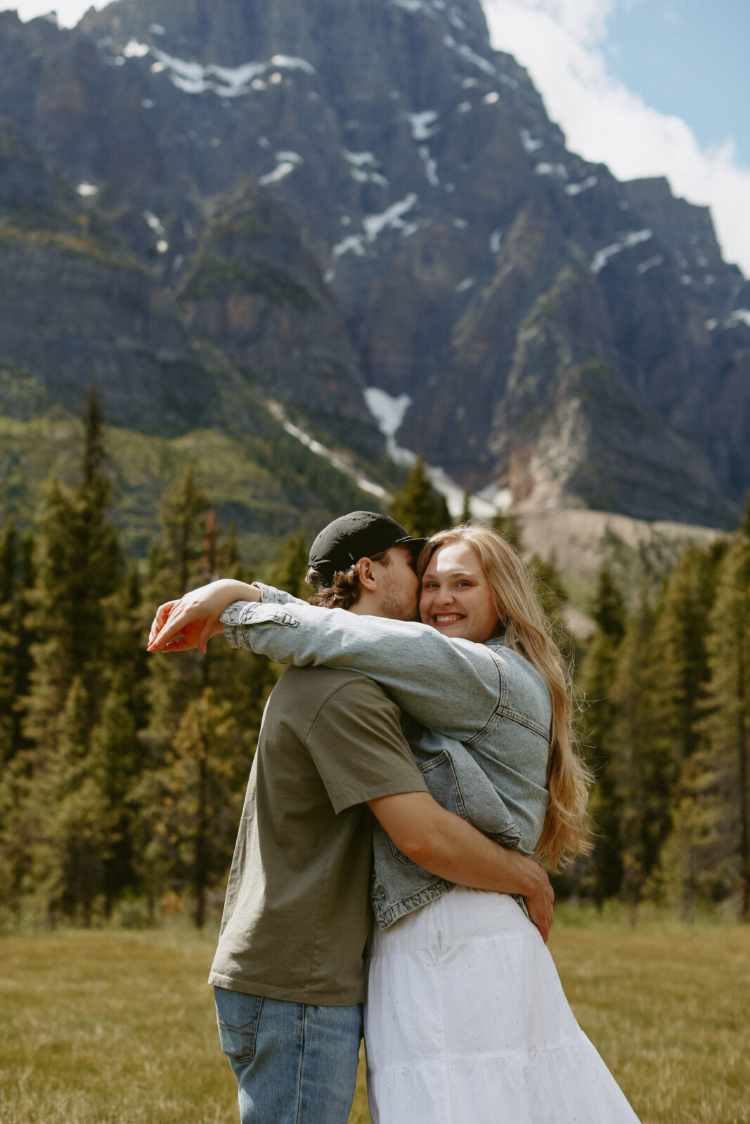Couple hugs during engagement photoshoot with mountains in the background