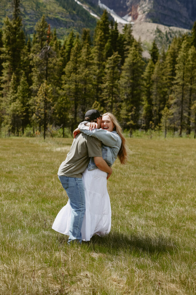 Couple laughs during engagement photoshoot with mountains in the background
