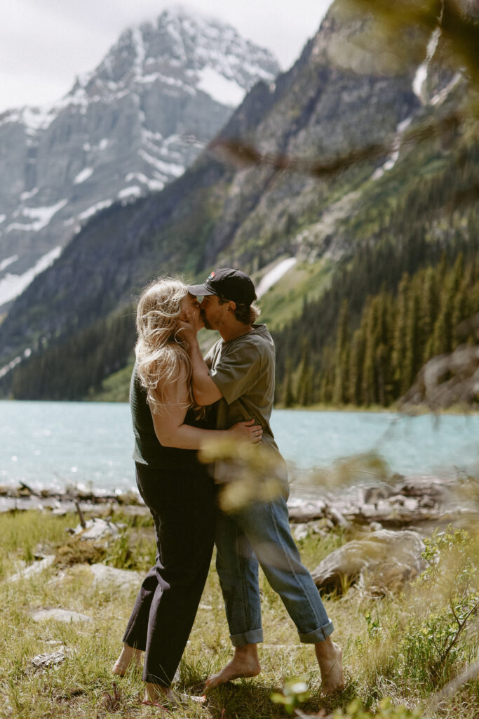 couple kisses with lake and mountains in the background