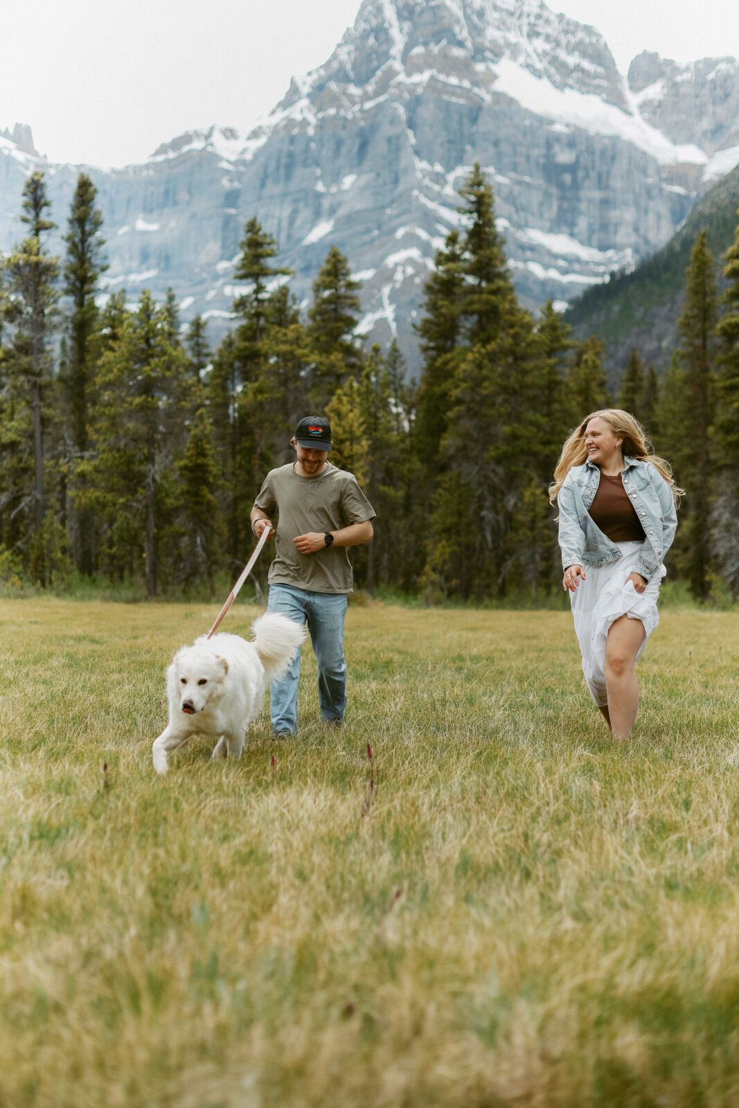 Couple and their dog during engagement photoshoot with mountains in the background