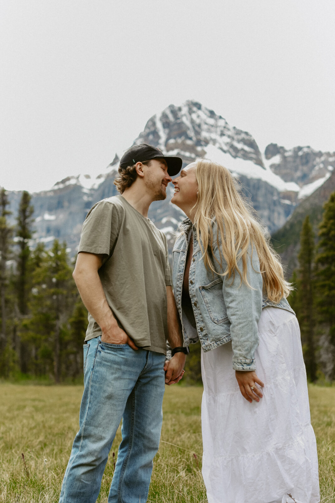 Couple laughs during engagement photoshoot with mountains in the background