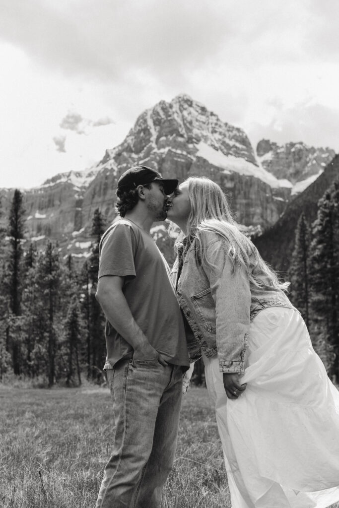 Couple kisses during engagement photoshoot with mountains in the background