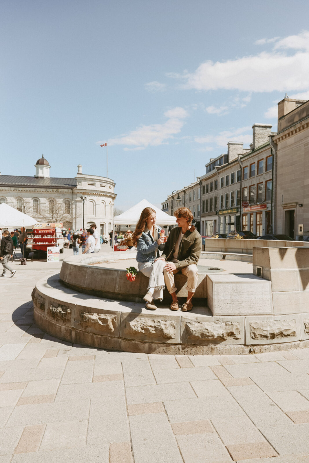 Couple sit on fountain edge with tulips and ice cream. Kingston, ON engagement photoshoot 