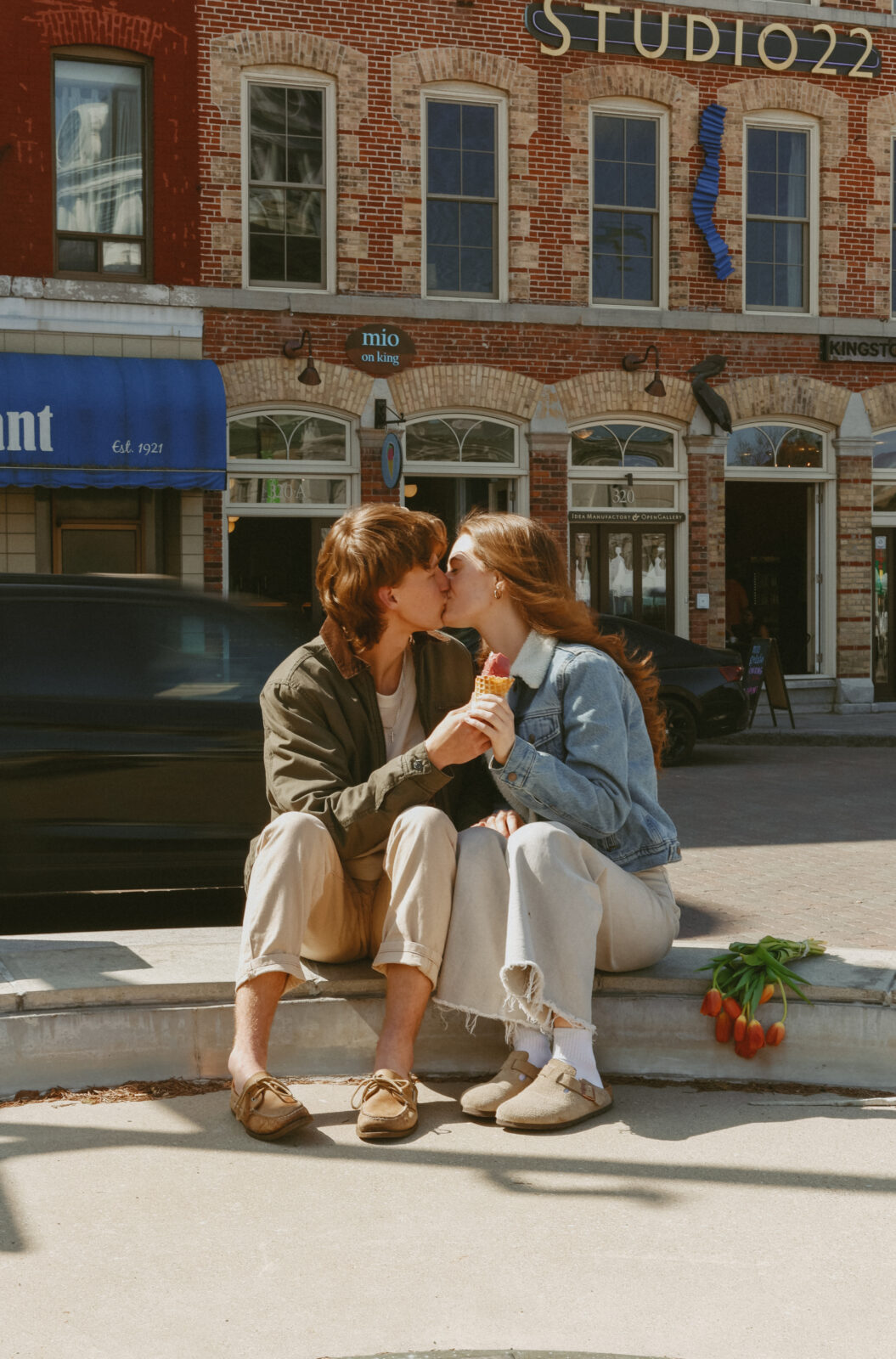 Couple kisses while holding ice cream   cone. 