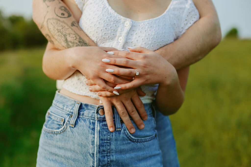 Couple up on a couples hands. With a focus on a engagement ring.