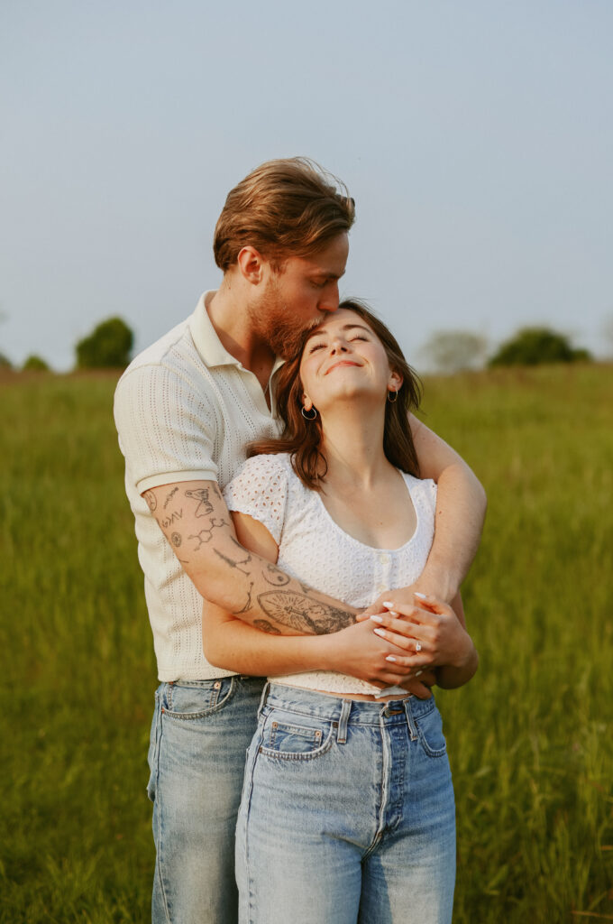 Couple hugs while man kiss woman on the forhead