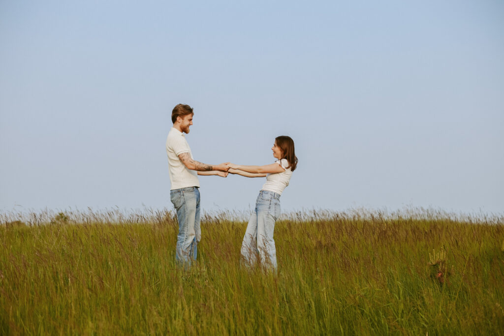 Couple holds hands in a field