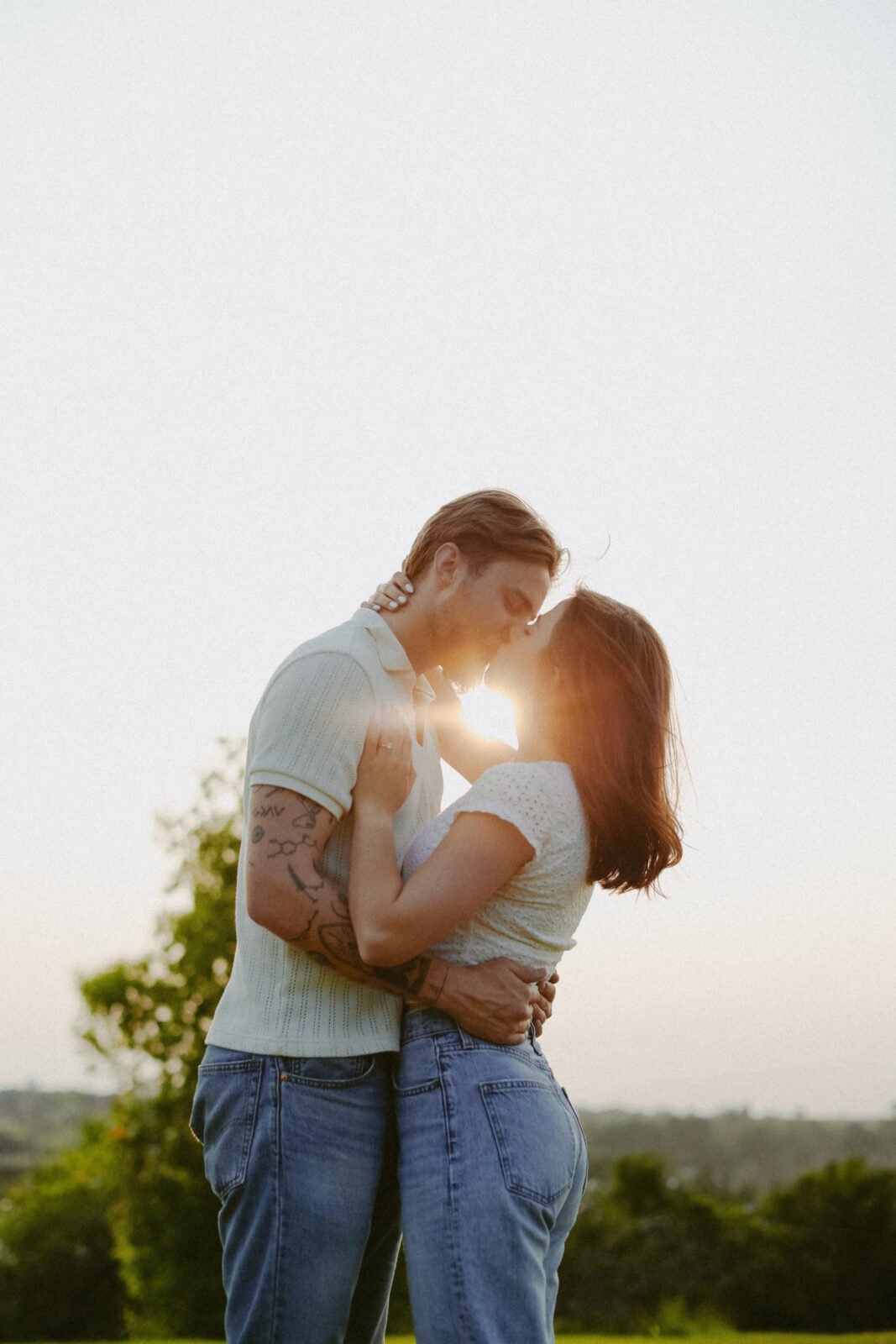 Couple kisses with sun shining on them. Engagement photography. 
