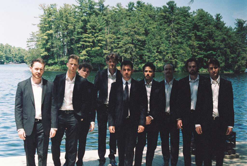 Groom men pose together with lake in the background