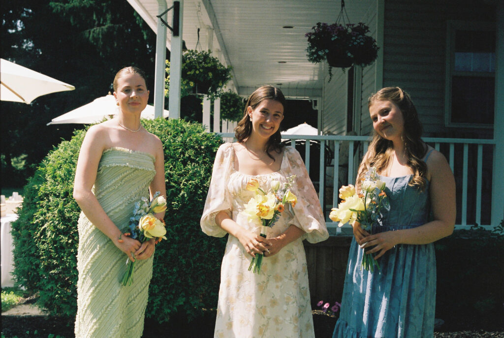 Bridesmaid with flowers smiling at camera.