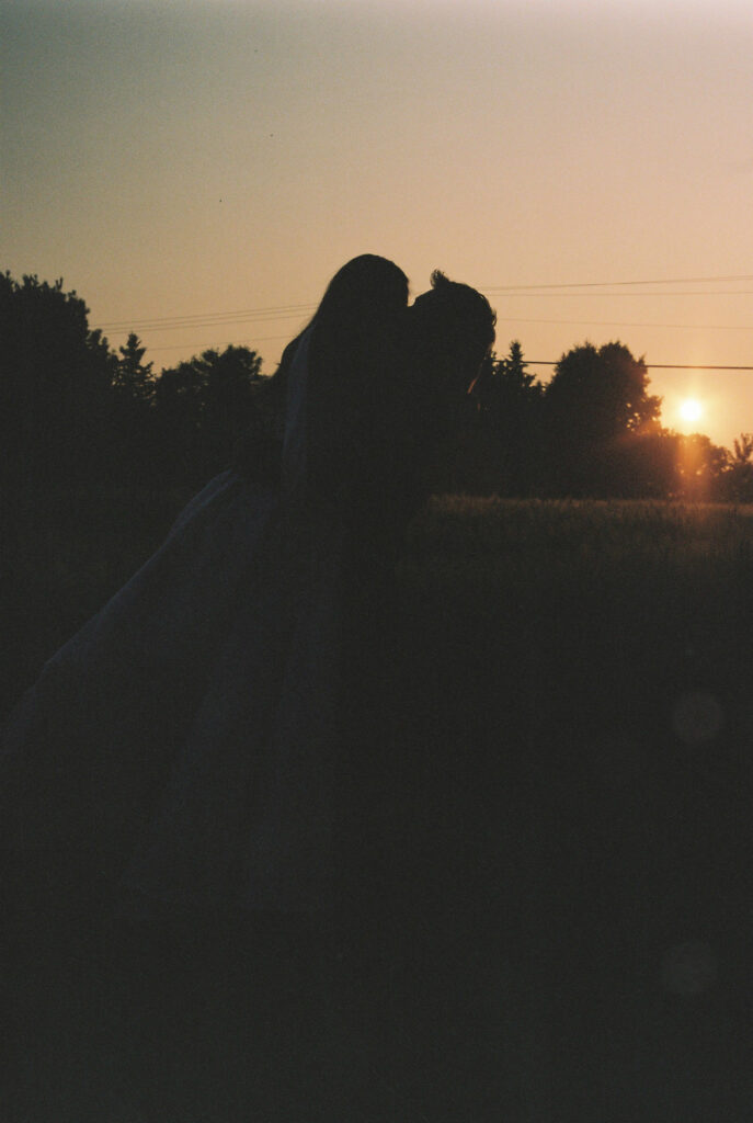 Groom lifts bride at sunset 
