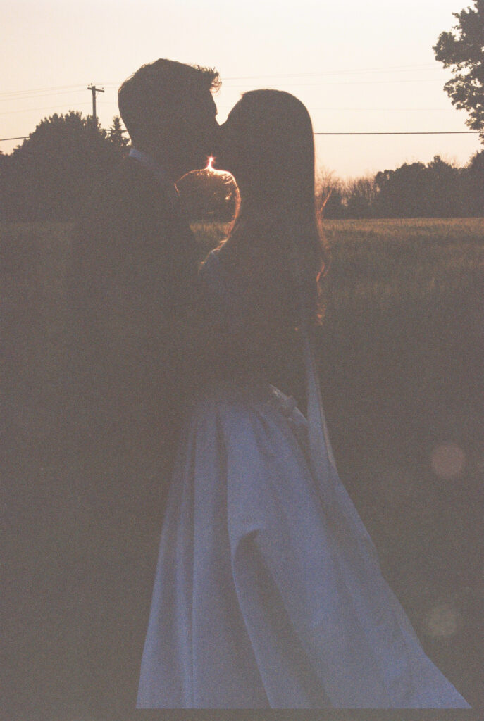 Groom lifts bride at sunset 