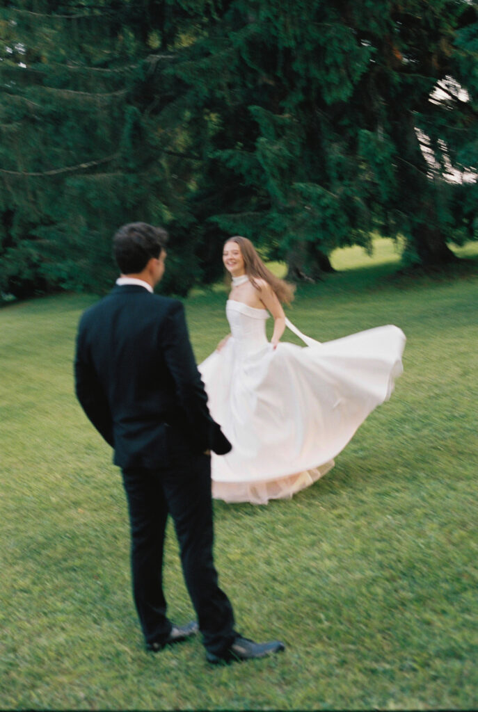 bride twirls her dress while groom watches 